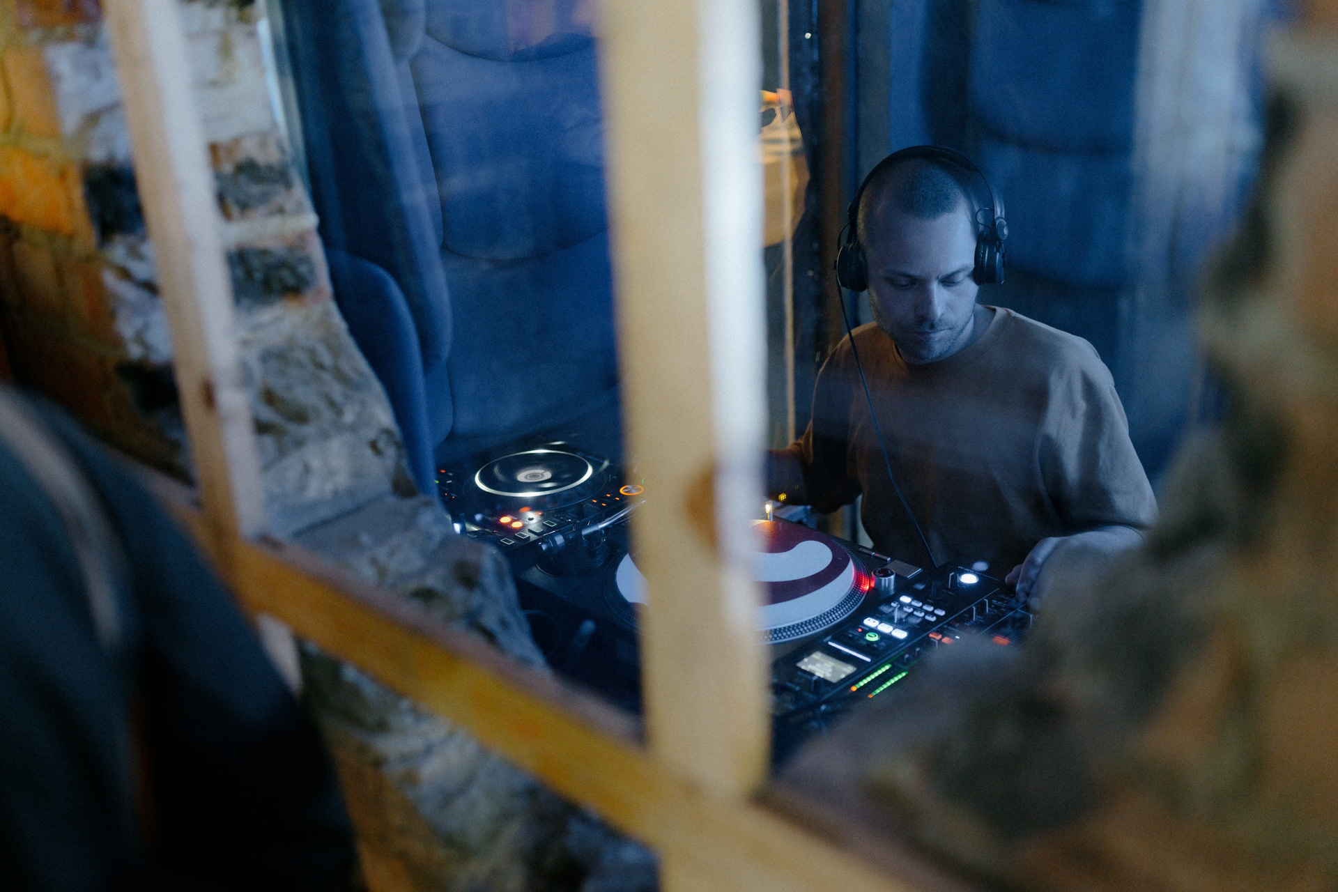 Man wearing headphones and mixing music equipment in a dark room.