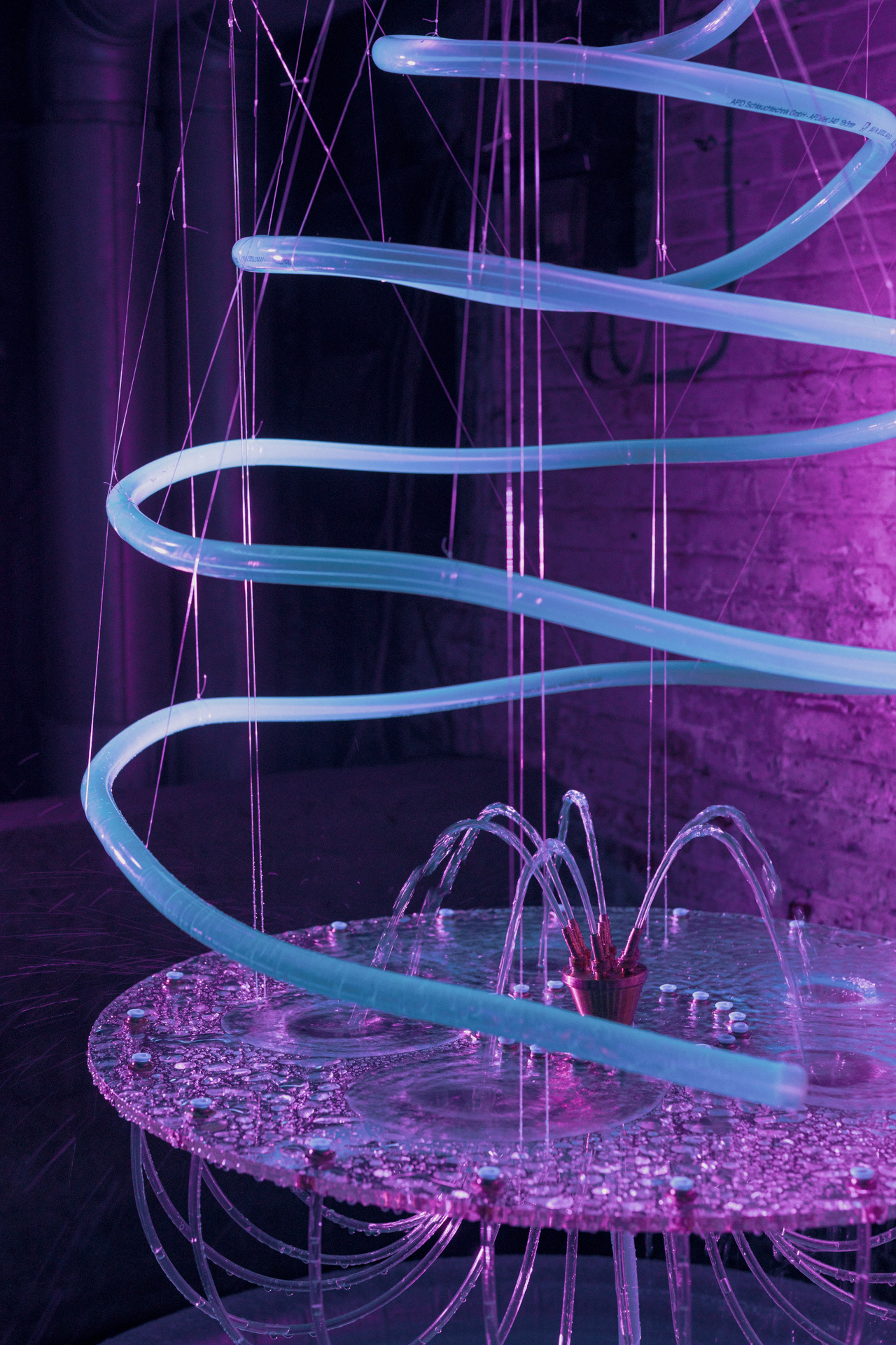 Curved glass tubes, pink and purple lighting, water features, abstract design.