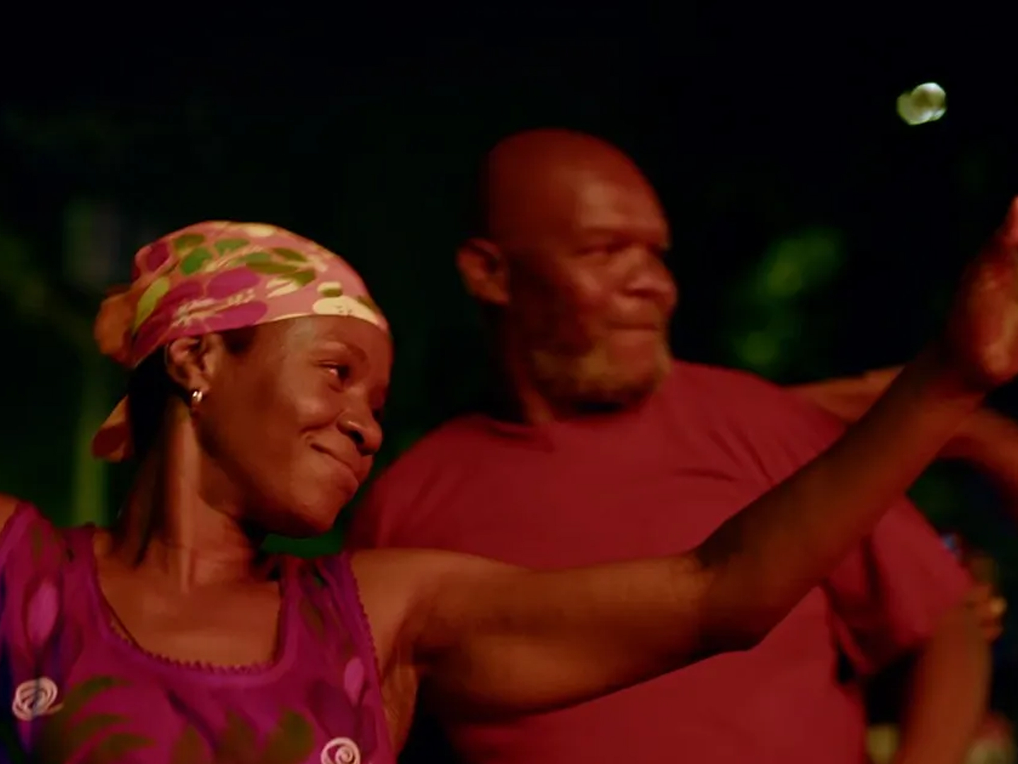 Two people in colourful clothing embracing outdoors at night.