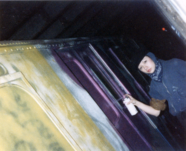 Person in dark hoodie on underground escalator, yellow and purple striped steps, dim lighting with motion blur effects.