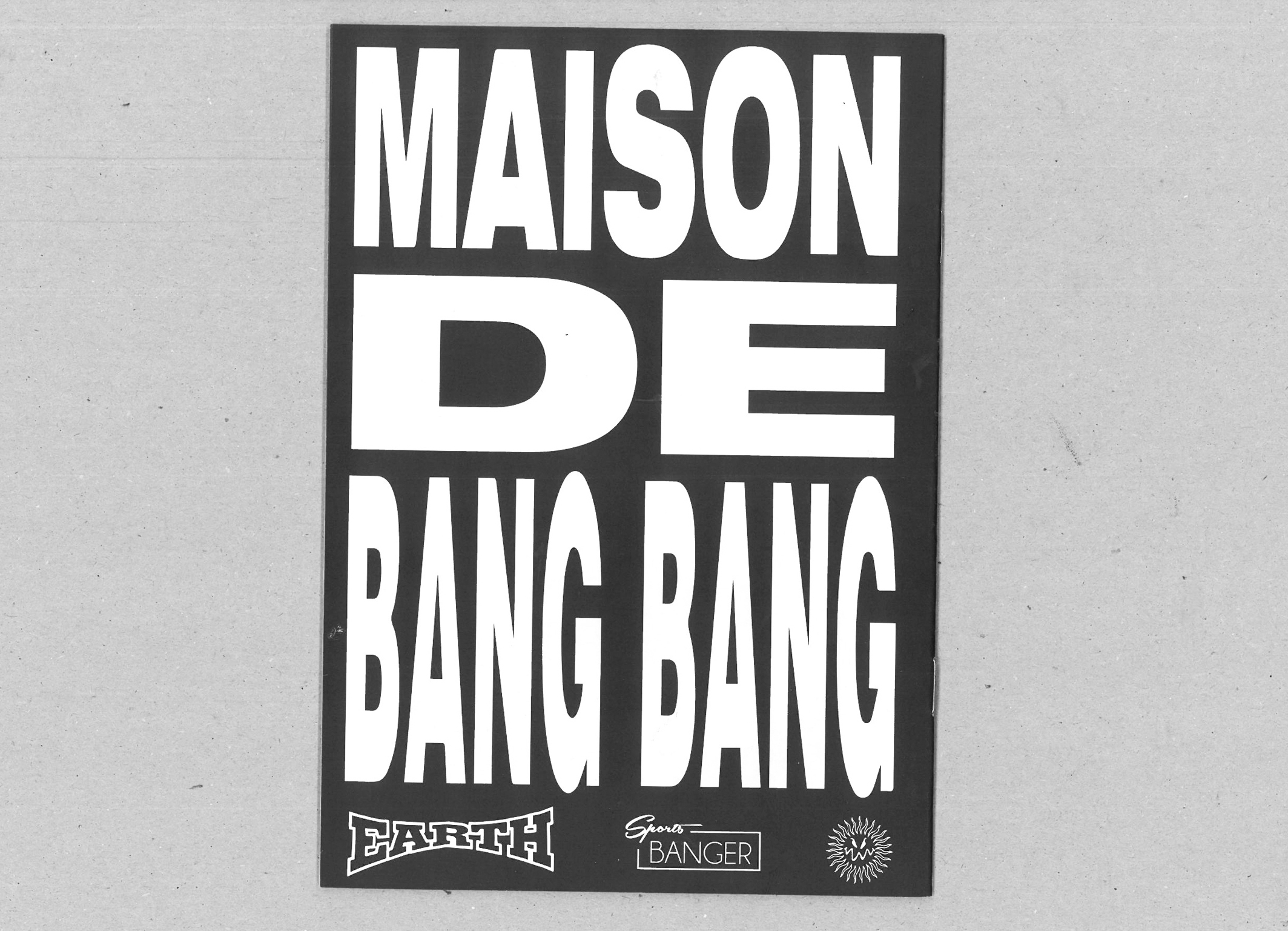 Black rectangular poster with white text reading "MAISON DE BANG BANG" in bold sans-serif typography, with small logos at bottom.