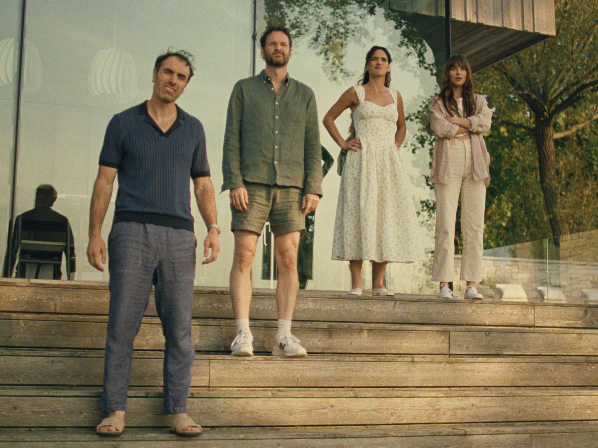 Four adults standing on wooden steps, wearing casual summer attire.