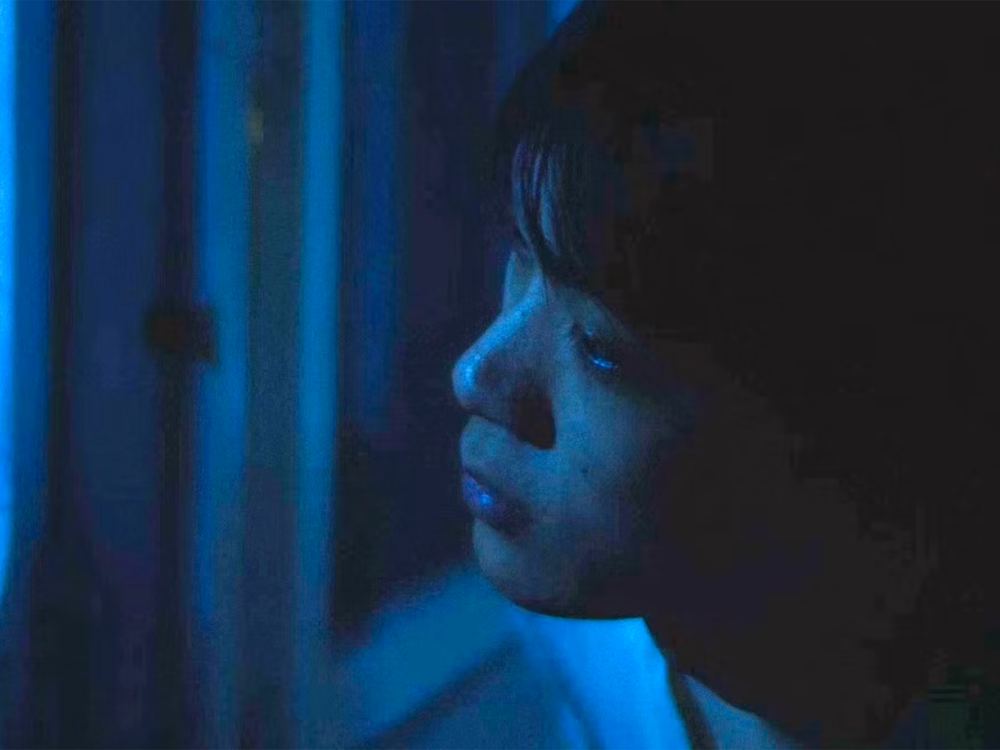 Person's profile illuminated in blue light against dark background, with vertical blue light streaks on the left side.