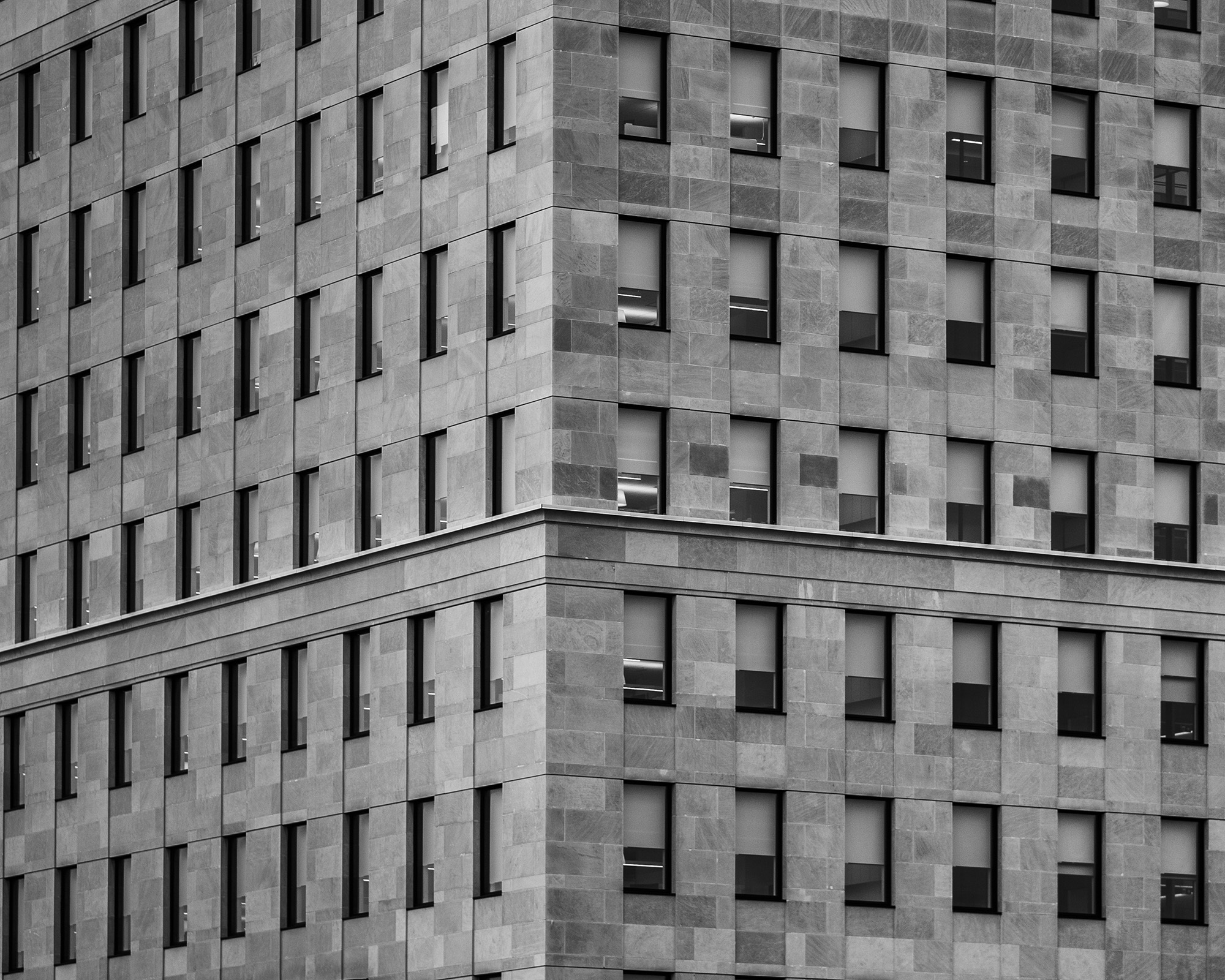 Geometric grid of windows in a monochrome concrete building facade.