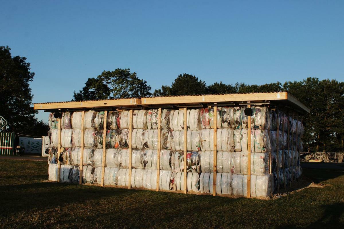 Small agricultural building with corrugated metal siding covered in peeling paint and rust stains, surrounded by green grass and trees.