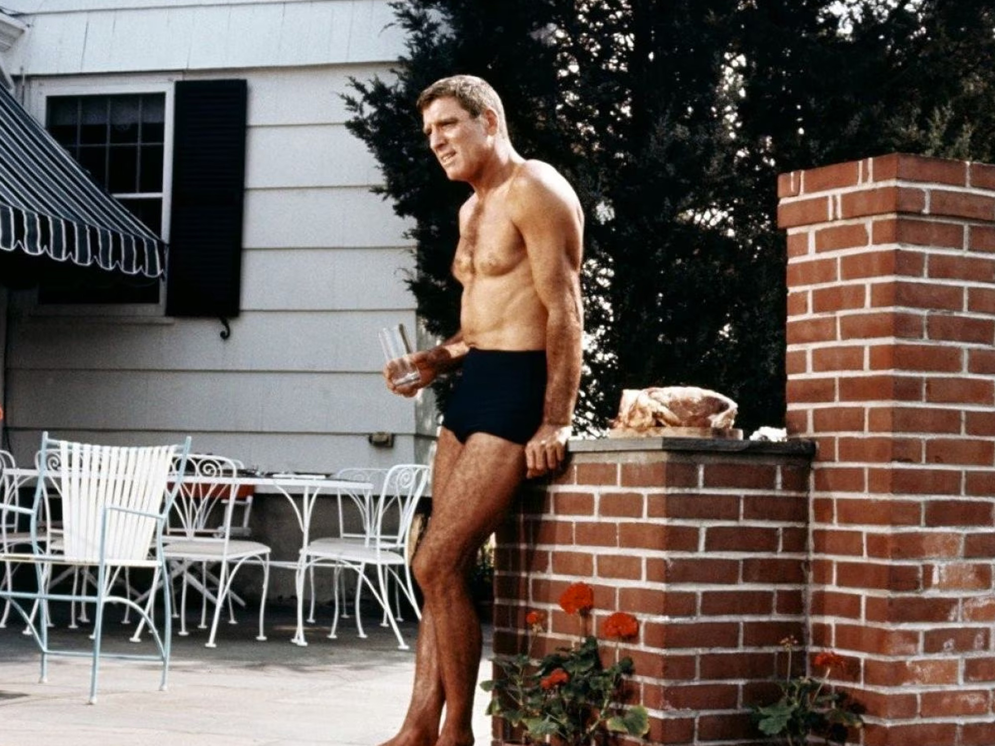 Shirtless man with muscular build standing on brick wall