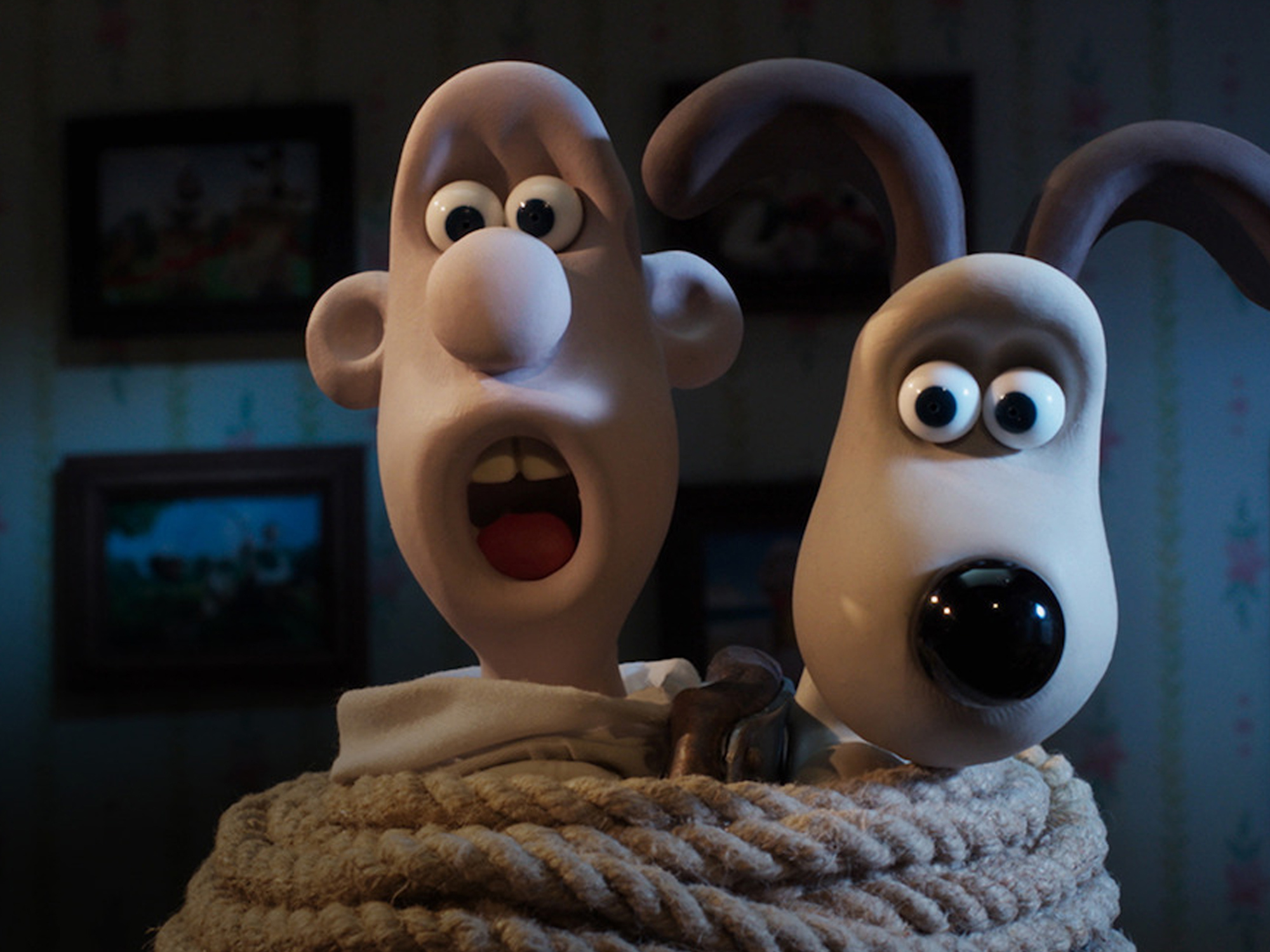 Cartoon characters Wallace and Gromit with exaggerated facial expressions and expressions against a dark background.