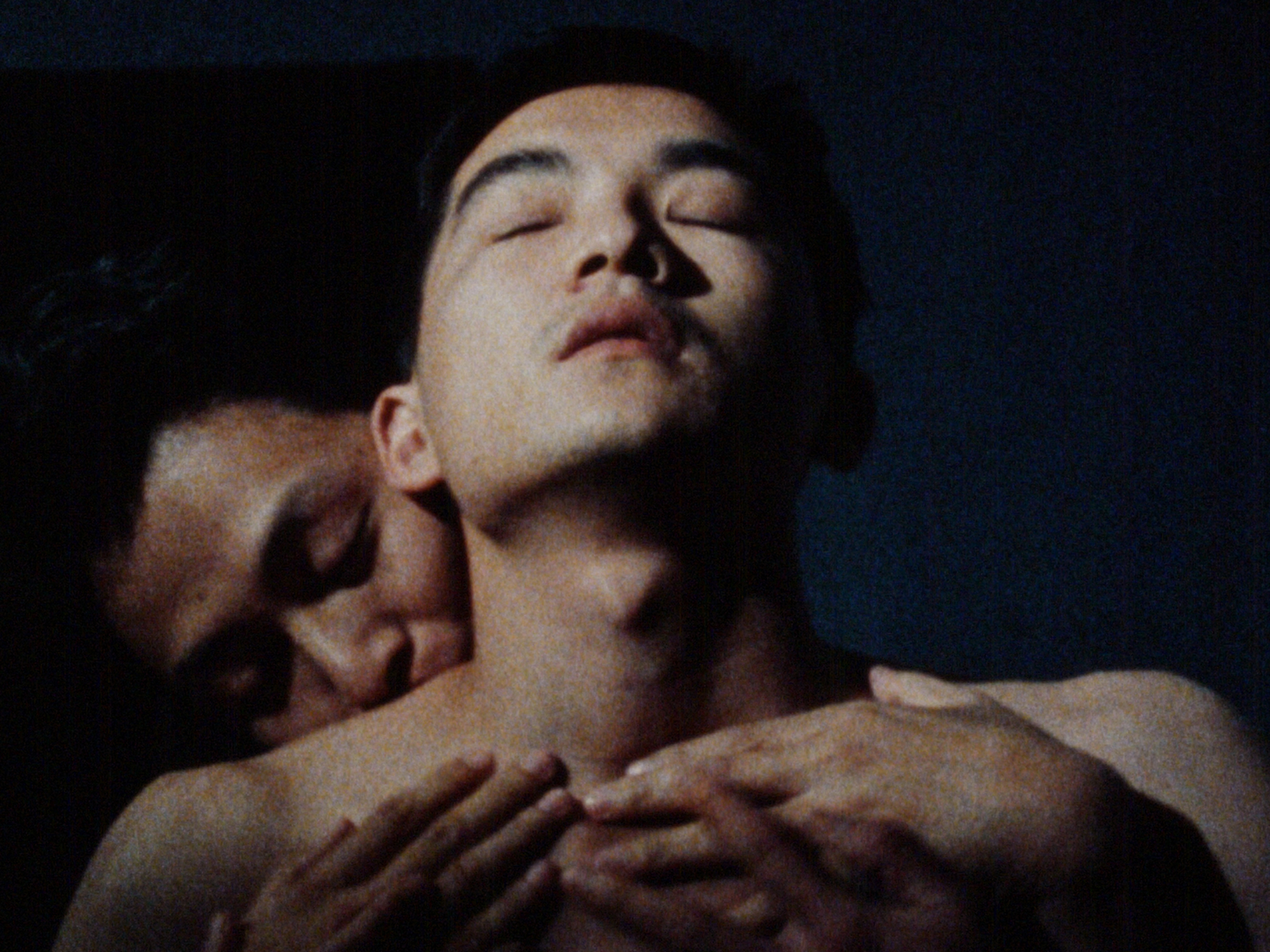 A close-up image of two shirtless Taiwanese men standing together in an embrace.