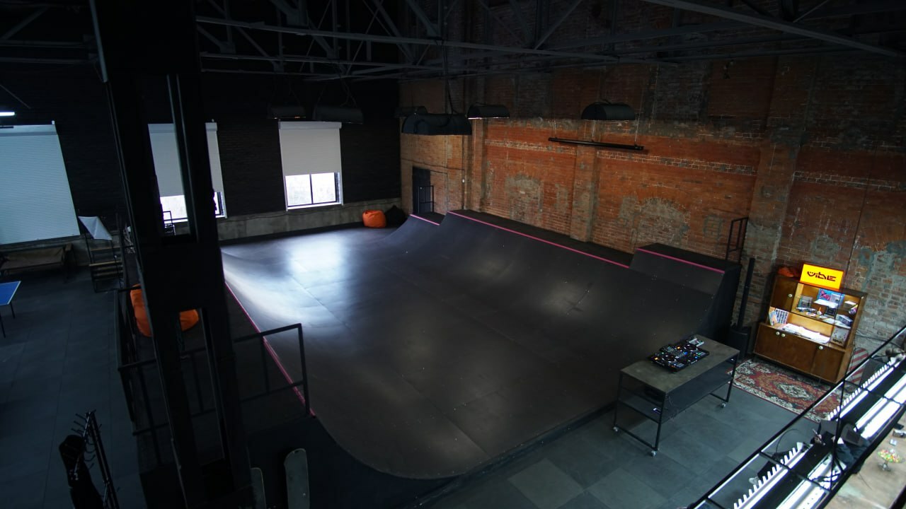 A large, empty indoor space with concrete flooring, wooden walls, and some equipment.