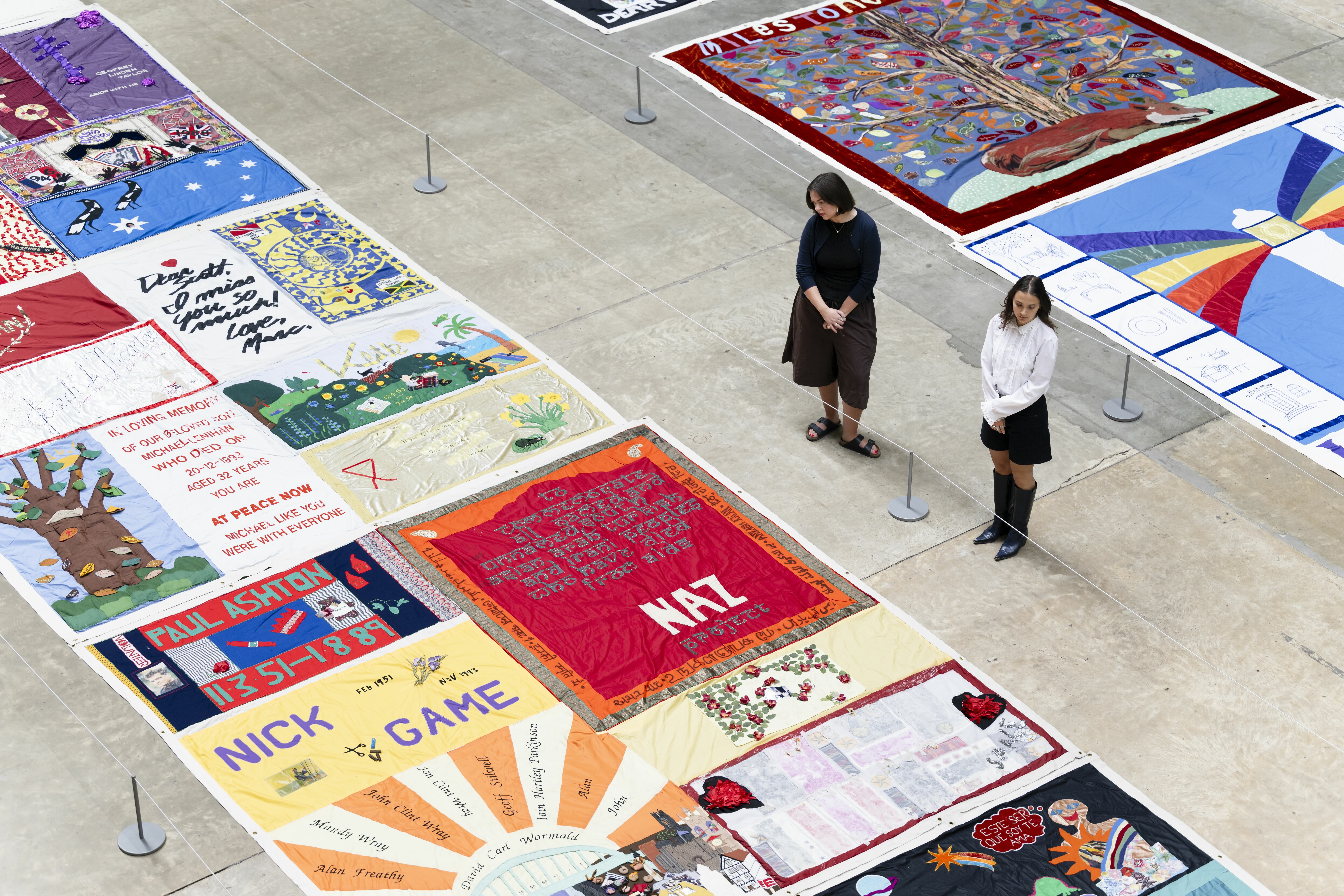Colourful exhibition with posters, artwork, and people walking through the space.