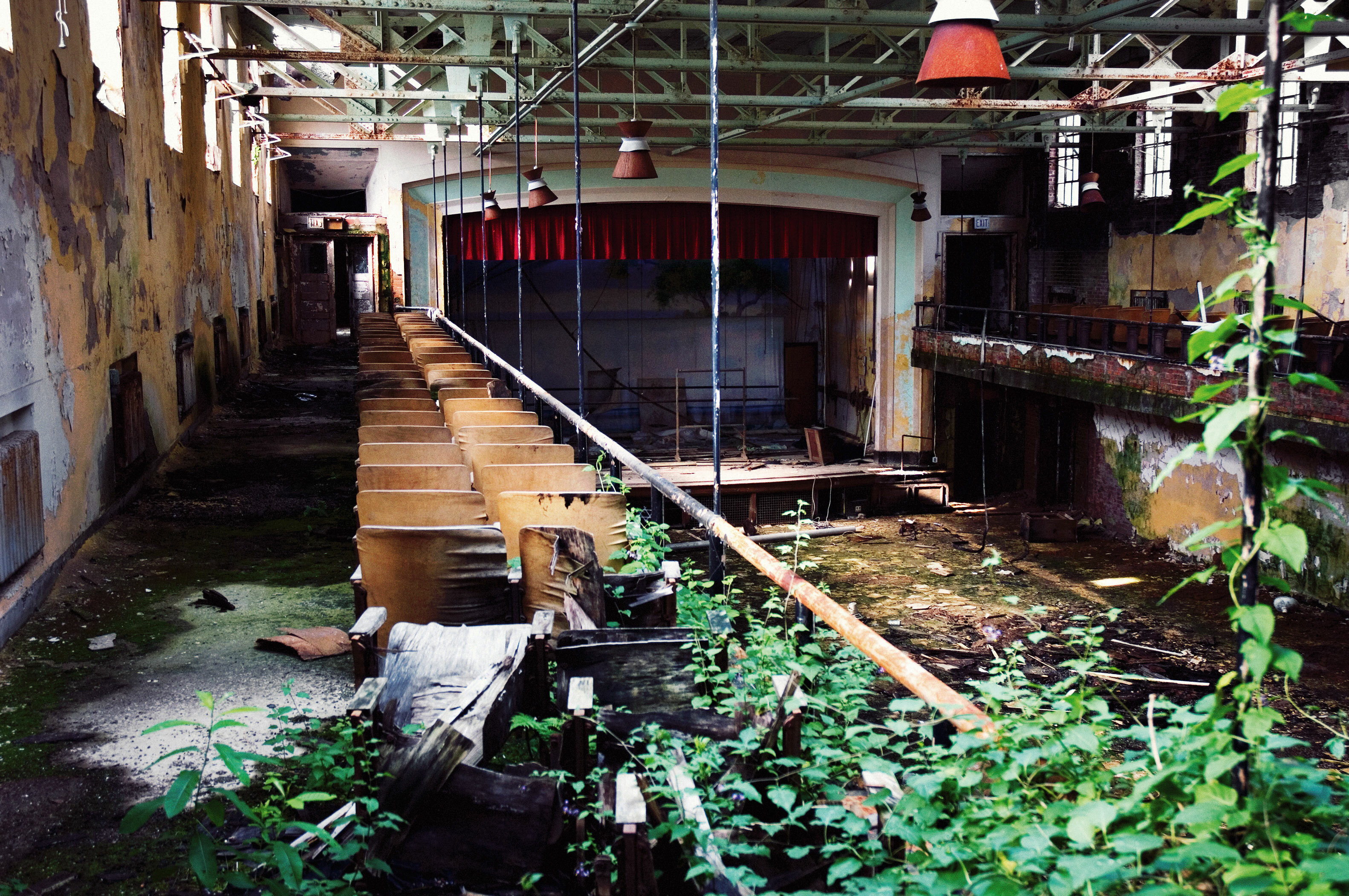 Dilapidated interior of an abandoned building, with overgrown vegetation and decaying furniture.
