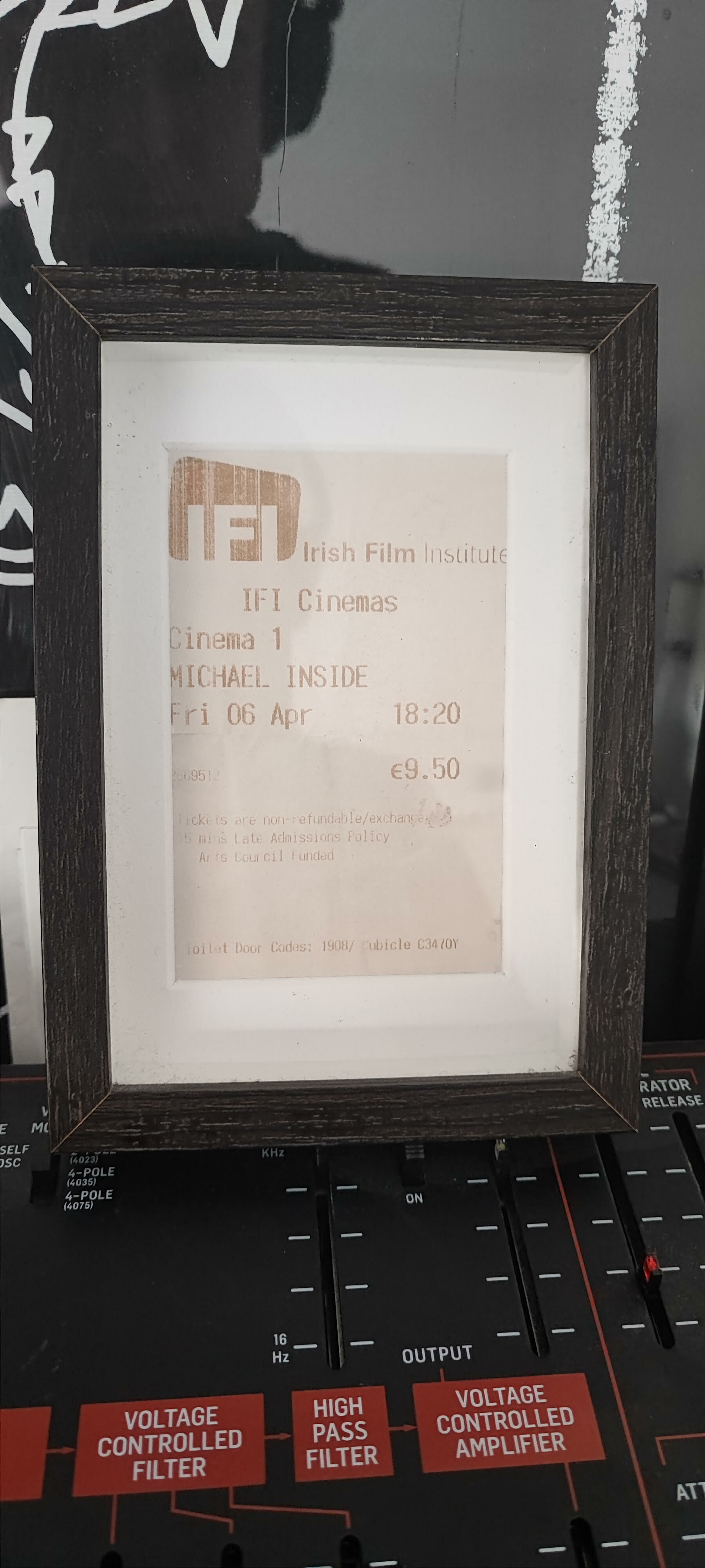 Framed cinema ticket for "Michael Inside" from Irish Film Institute displayed on black audio equipment with red control labels.