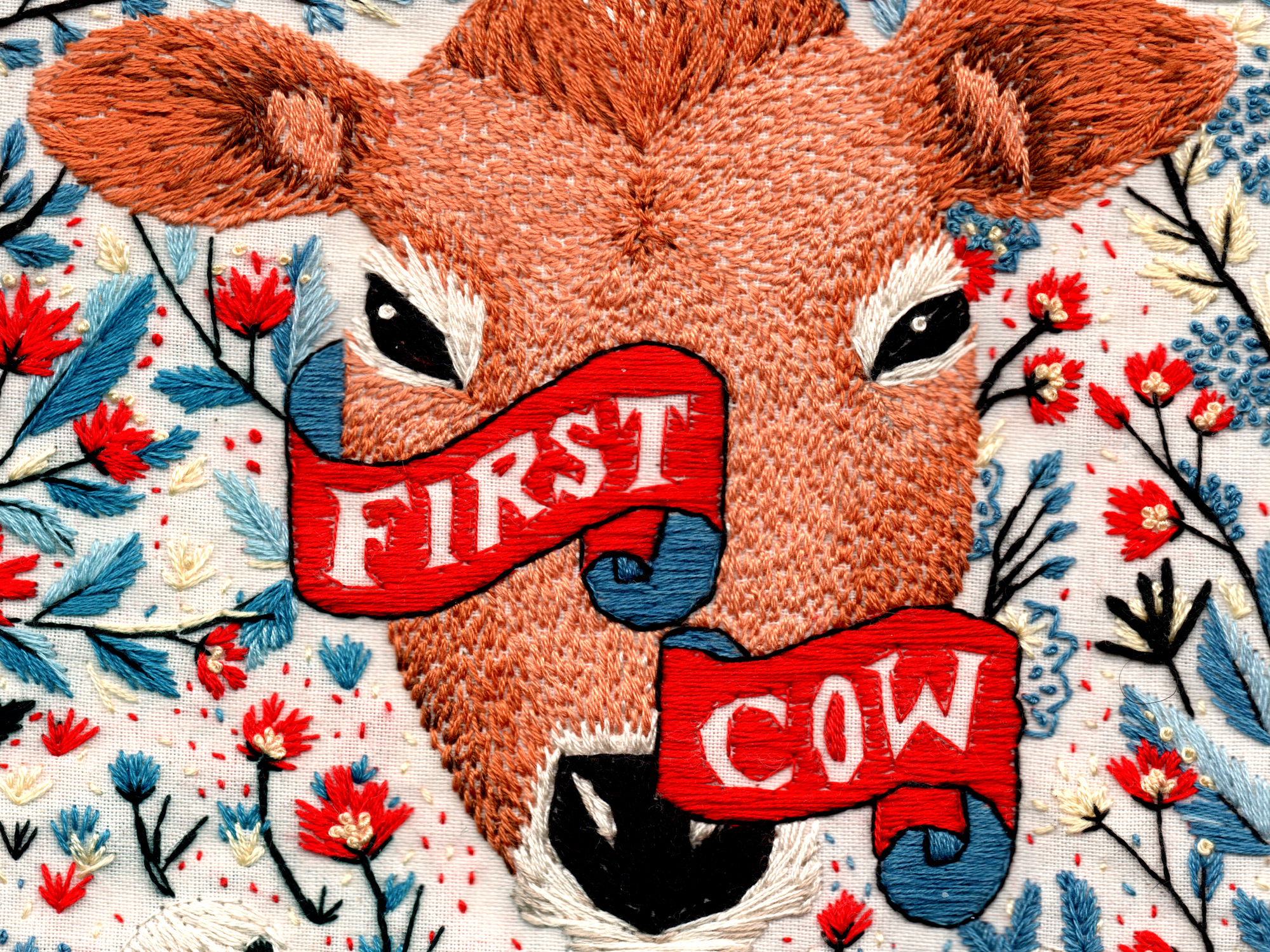 A brown, furry cow wearing a "First Cow" sign, set against a background of colourful flowers and plants.