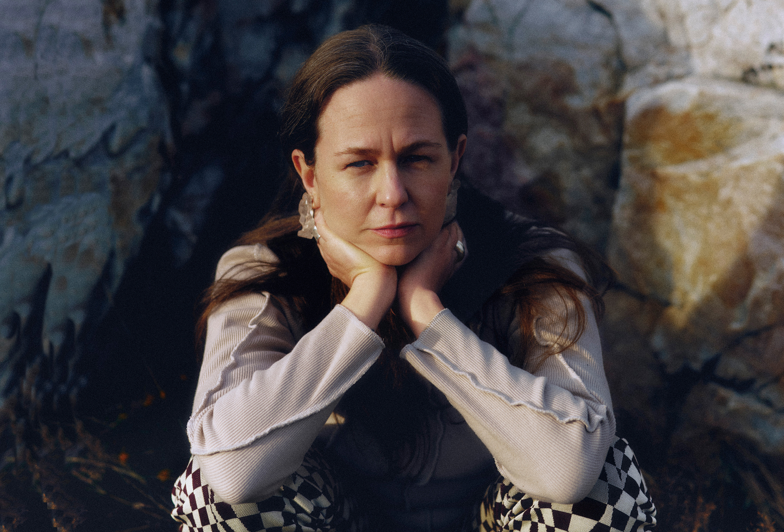 Alice Boman with her hands around her neck, looking directly into the camera