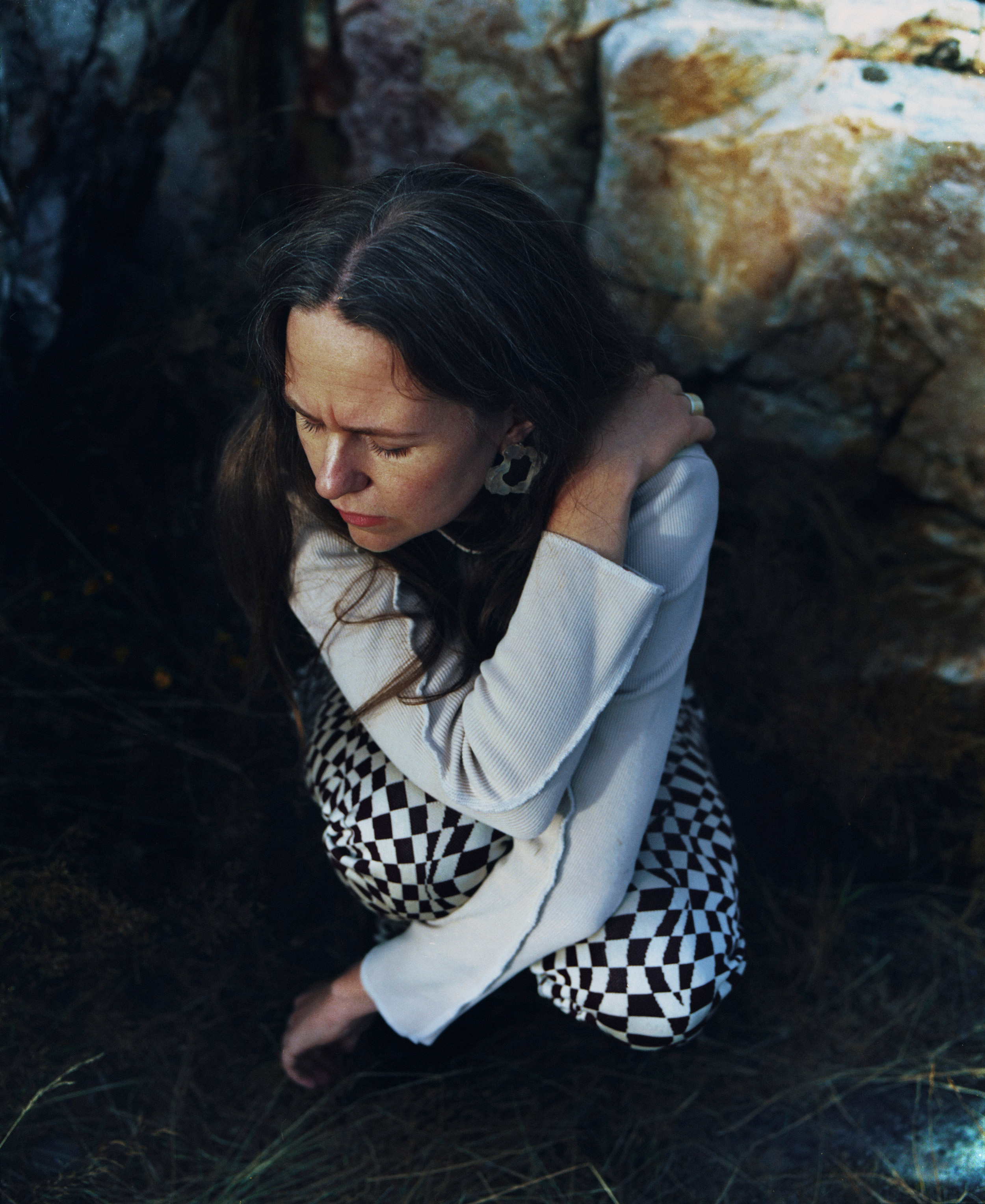 Alice Boman crouching with her arms crossed over her body, looking down to the ground