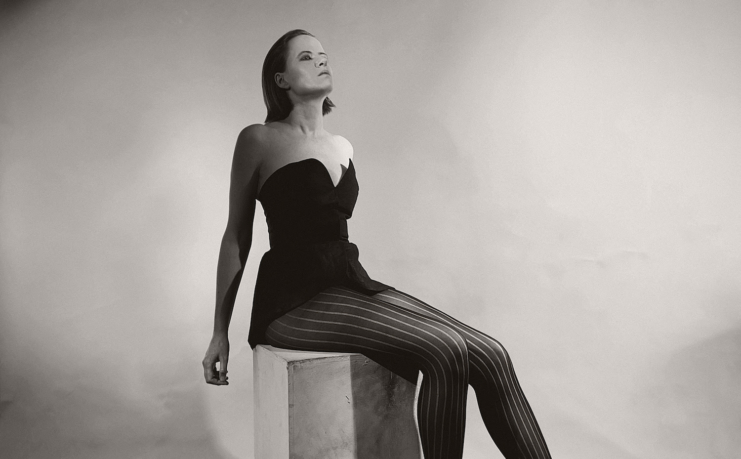 Amber Arcades sitting on stone plinth corset top