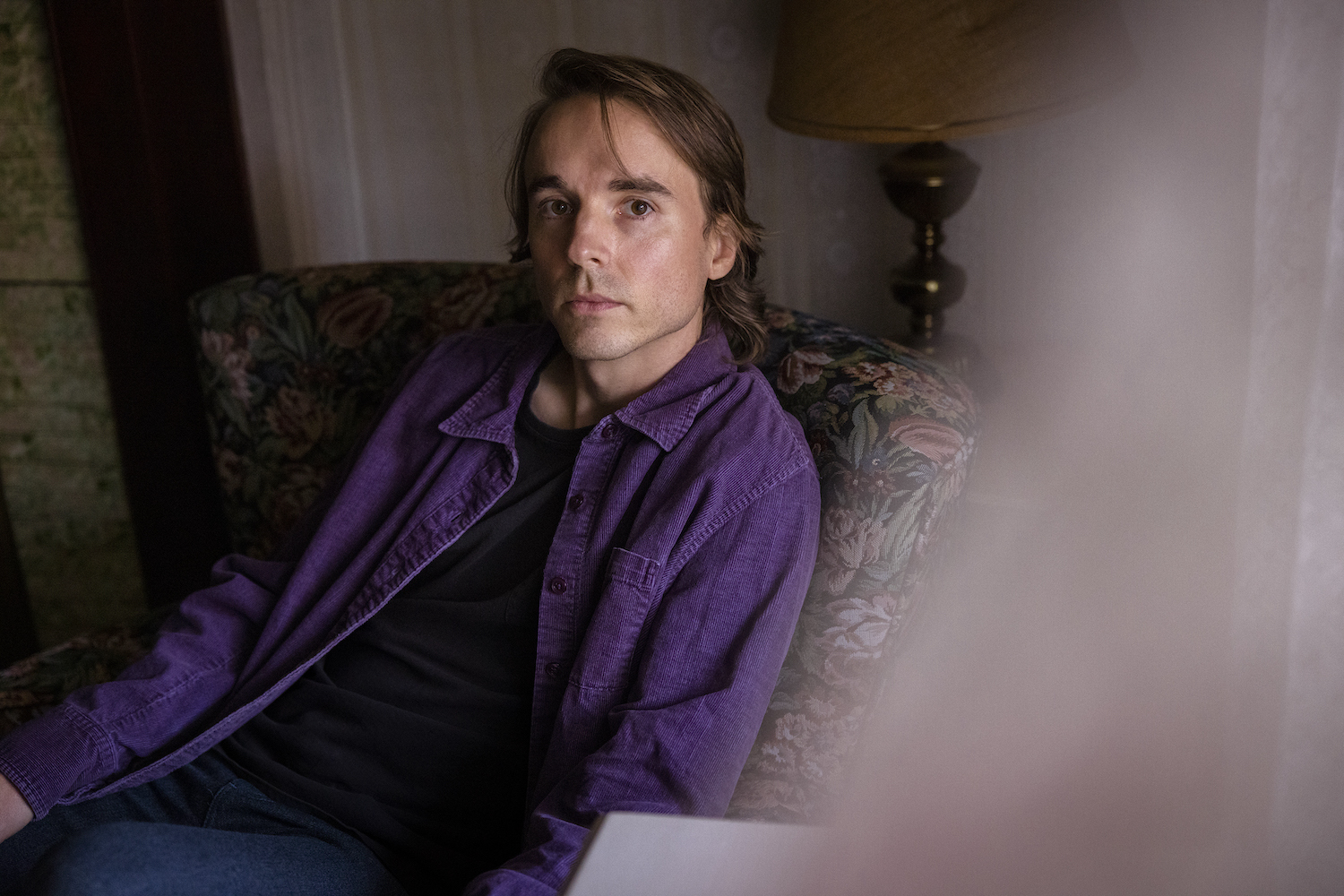 Andy Shauf sitting in floral chair in purple shirt