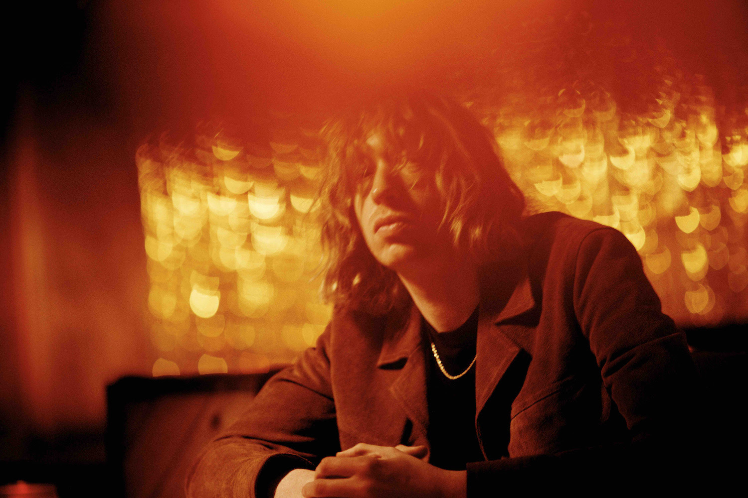 Daniel Avery seated in booth with red lighting for "Wall of Sleep" single