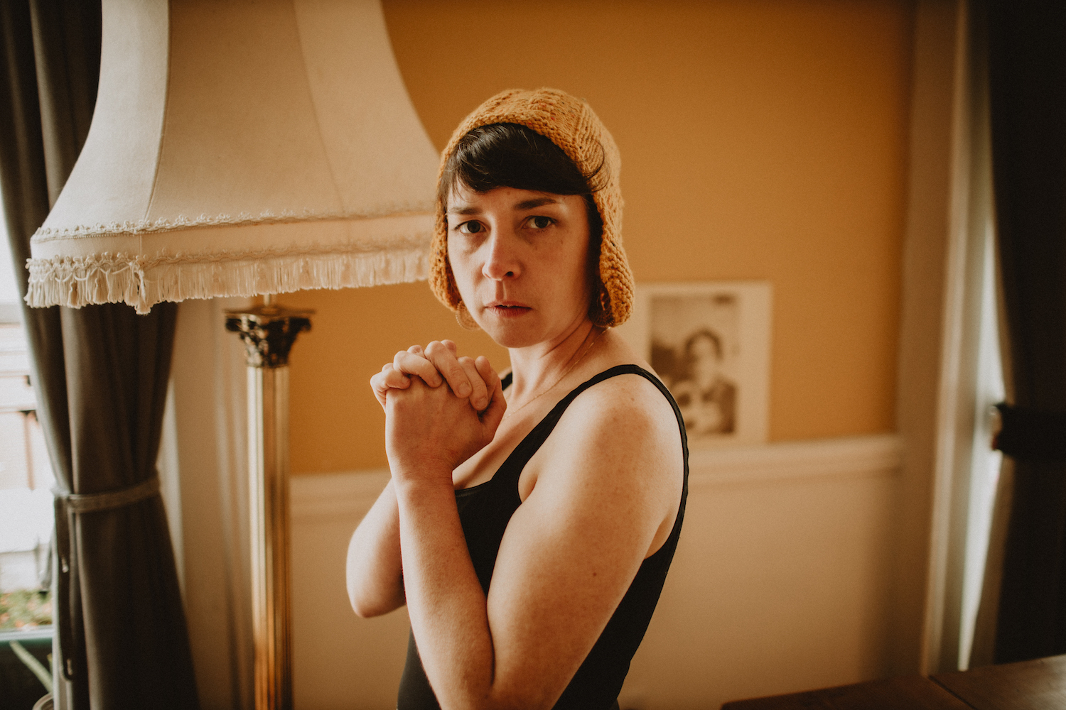 Lisa O Neill knitted hat black vest clasped hands