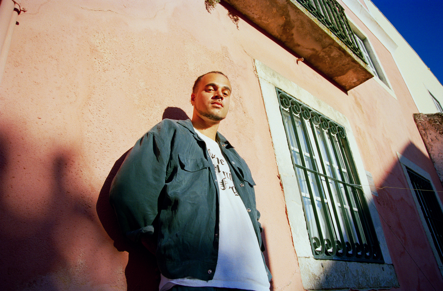 Louis VI leaning against pink building wall Lisbon