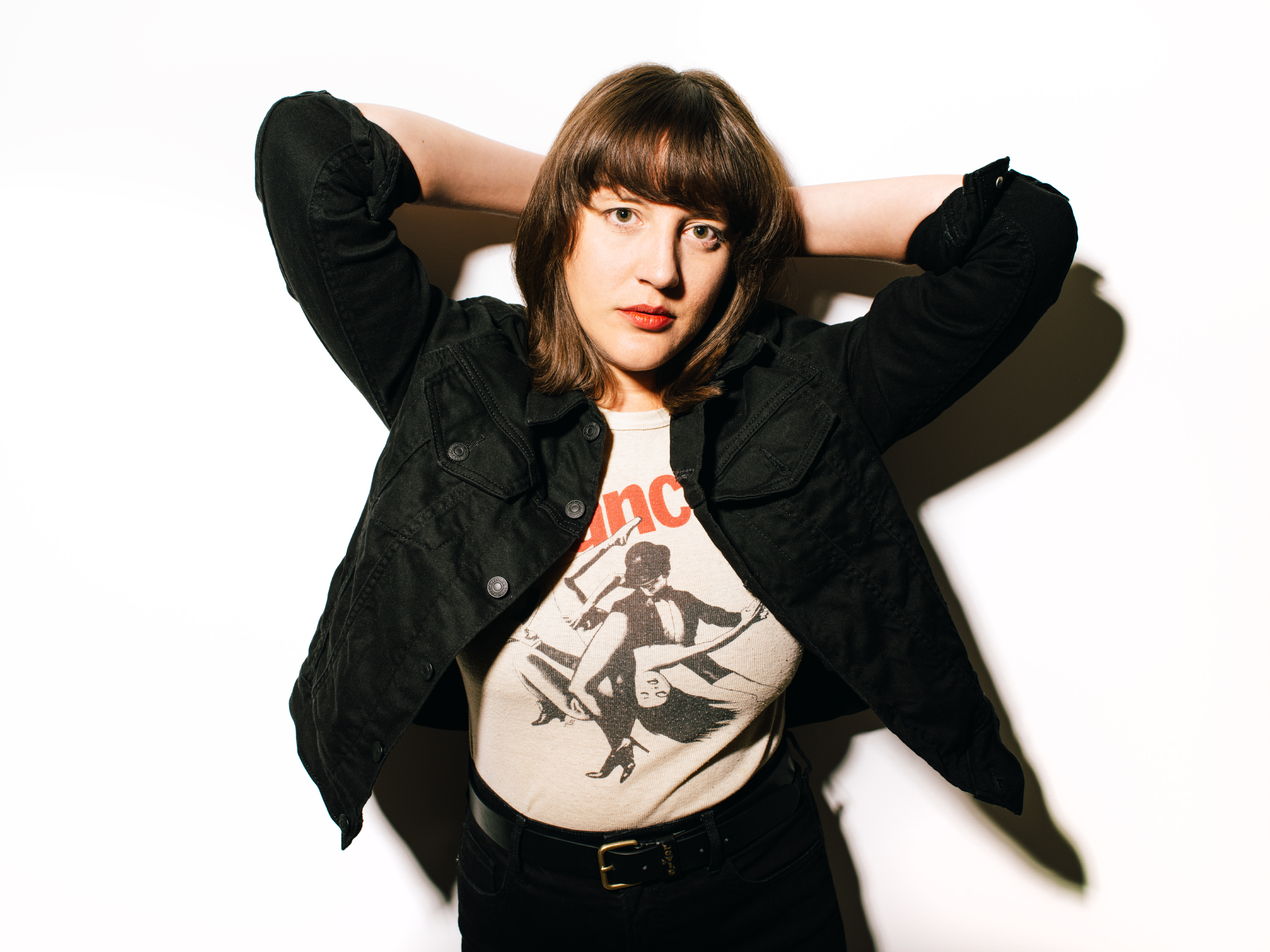 Caitlin Rose with arms raised behind her head, photographed against a plain white background