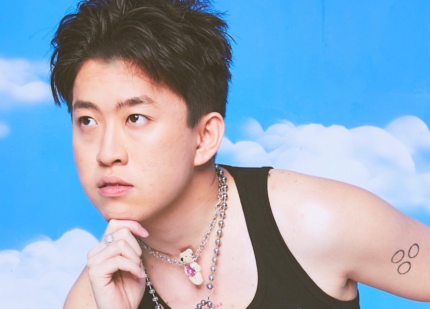 Rich Brian hand on chin blue sky backdrop