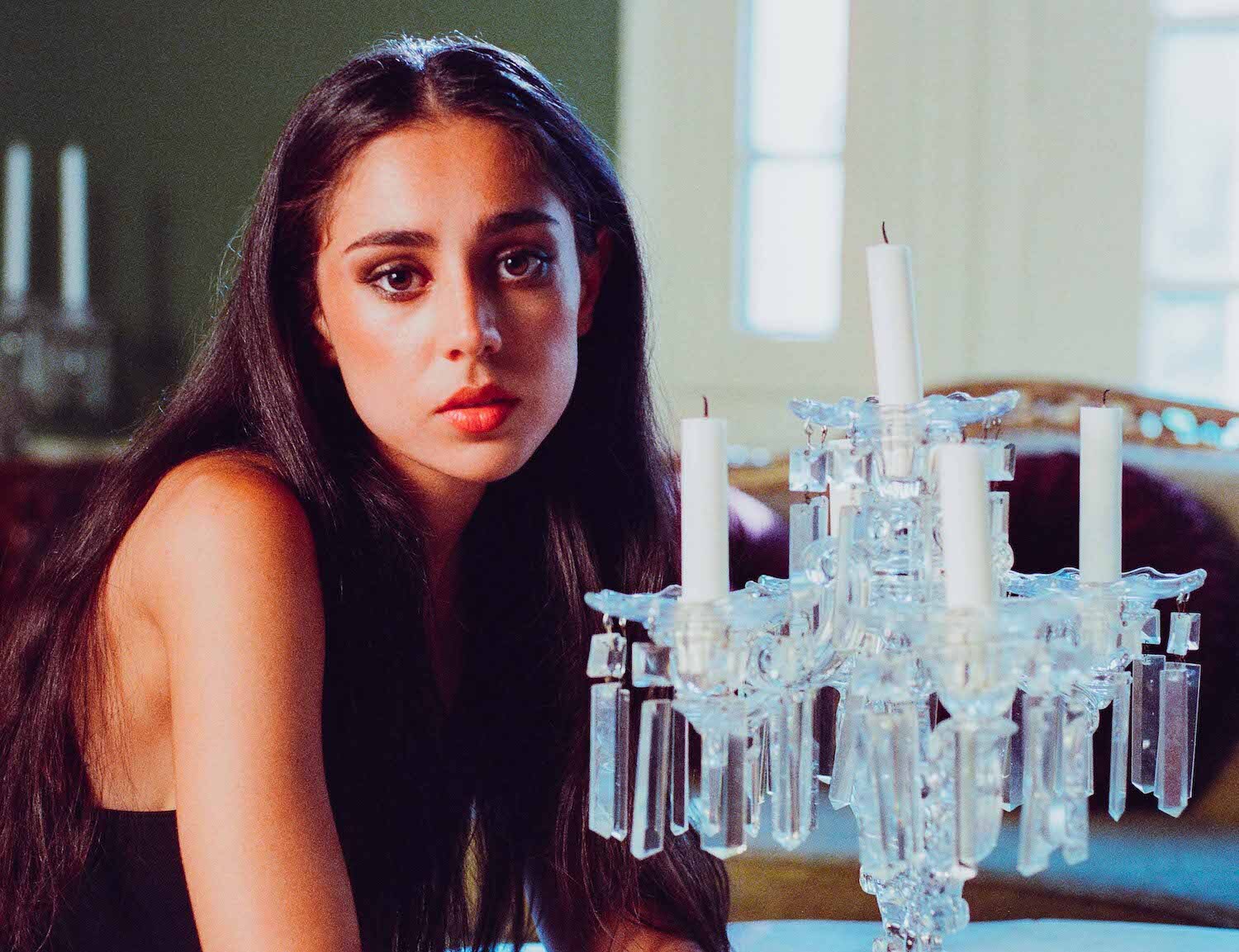 Samia sat at table with candle chandelier