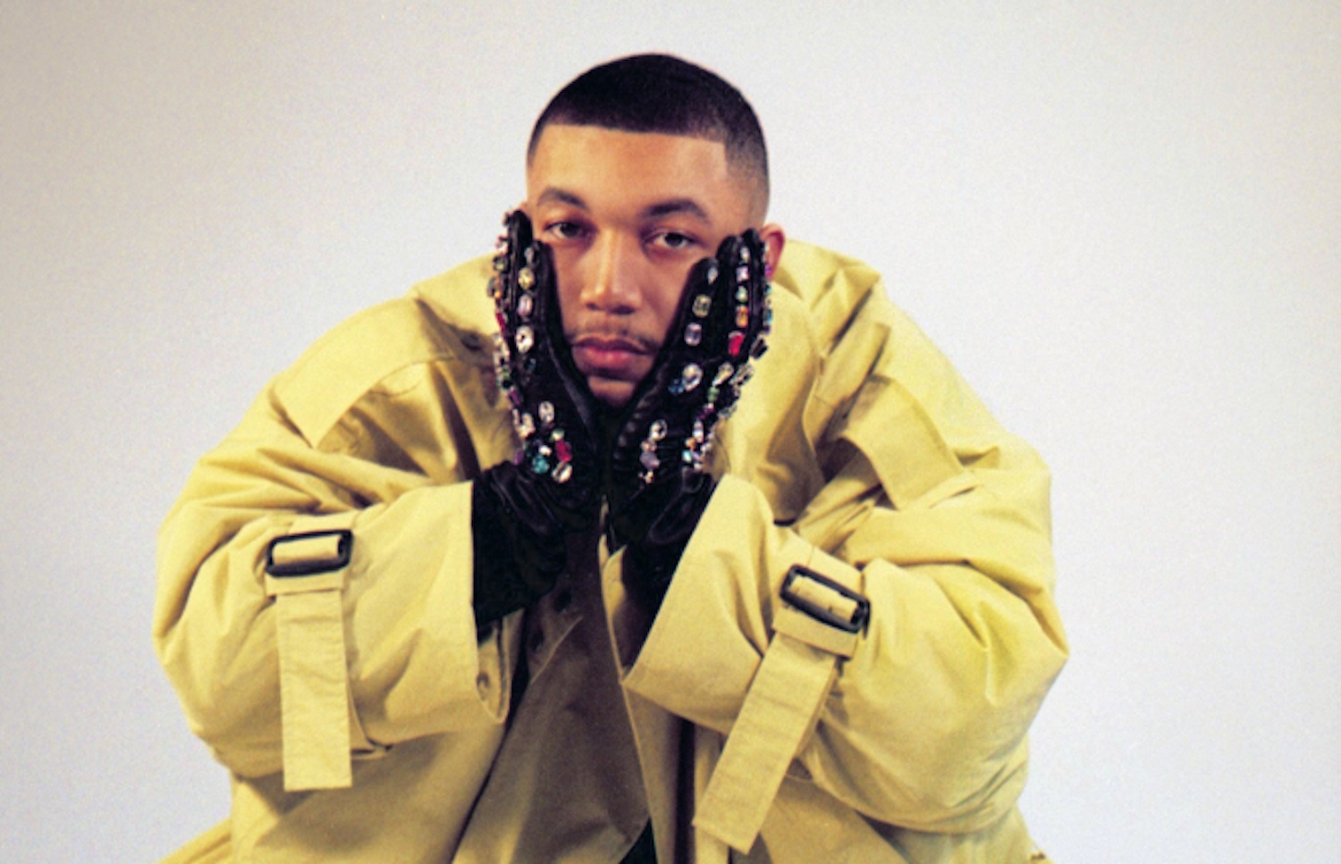 Wesley Joseph clutching face jewelled gloves yellow trench coat