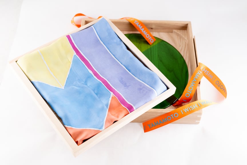 En lys treboks med et fargerikt silkesjal plassert inni.