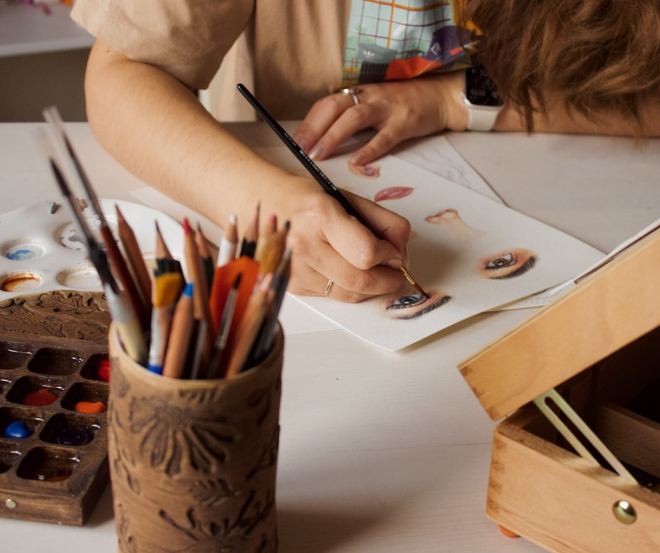 Woman painting a face  on paper with watercolours.