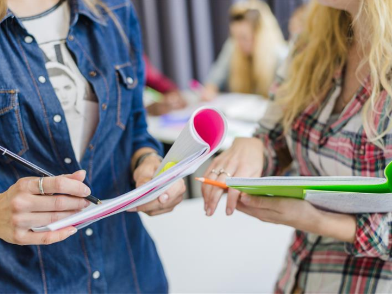 Students Holding Notebooks and Papers in Classroom