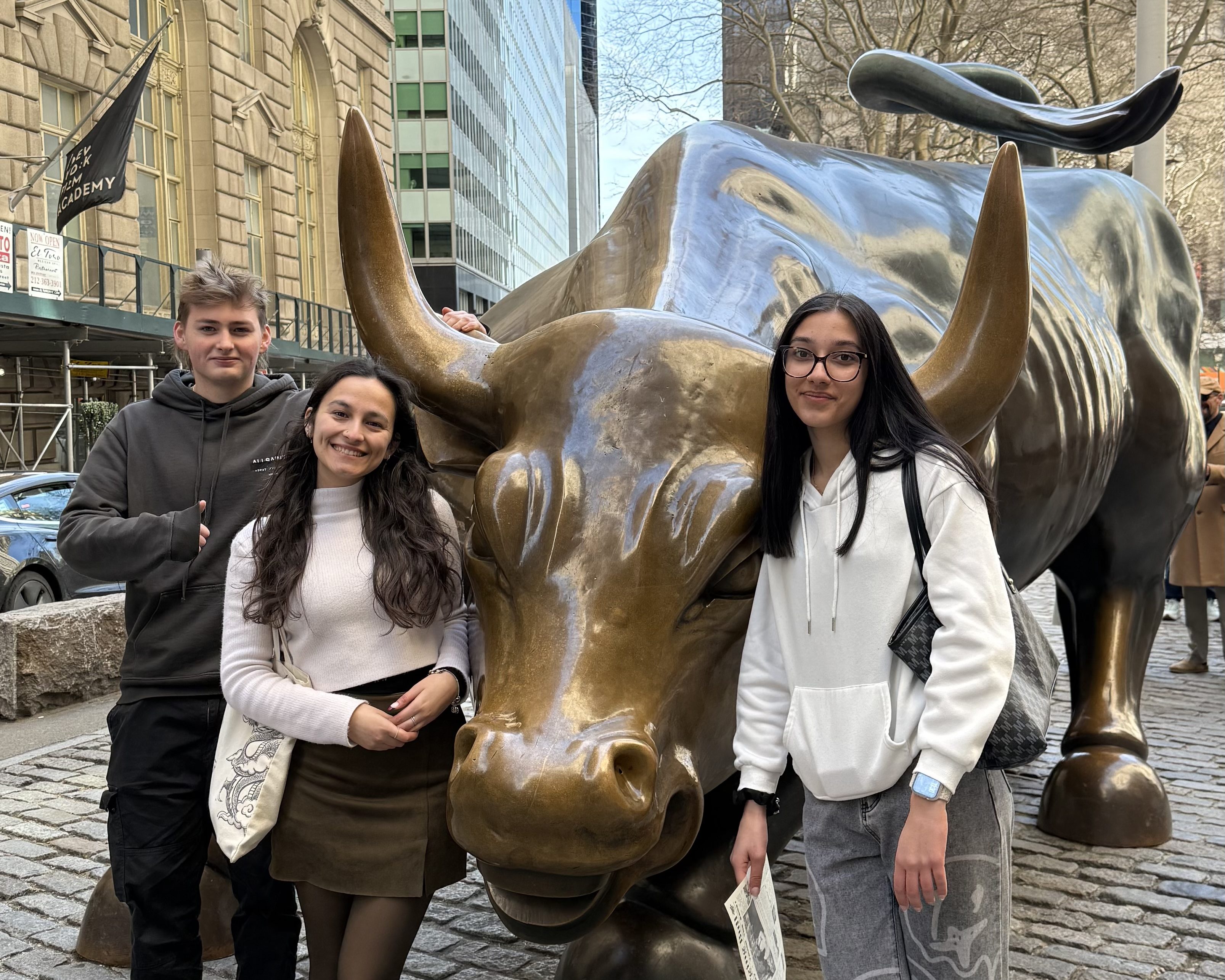 Students standing in front of a bronze bull during their visit to Wall Street on their New York trip.