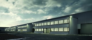 Unités de bureaux et d'entrepôt sur deux étages éclairées du site logistique Montea à Bornem, Belgique au crépuscule