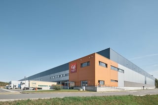 Entrepôt logistique Montea à Camphin-en-Carembault, France avec bardage gris, angle de bureaux orange et camions aux quais