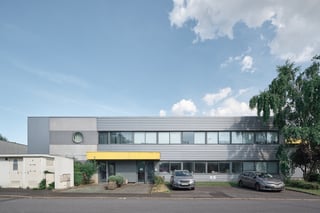 Site logistique Montea au Mesnil-Amelot, France : bâtiment de deux étages à façade métallique grise et auvent d'entrée jaune