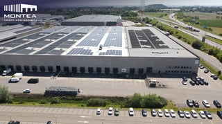 Luchtfoto van Montea-logistiekmagazijn in Milmort, Belgium met zonnepanelen op het dak en laadkades