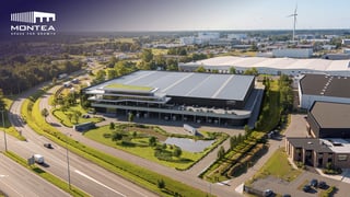 Vue aérienne de l'entrepôt logistique moderne de Montea avec cour végétalisée en toiture le long d'une autoroute à Puurs, Belgique