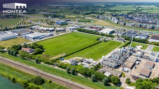 Vue aérienne d'un terrain logistique Montea à Zaltbommel, Pays-Bas, bordant un parc industriel et une voie ferrée