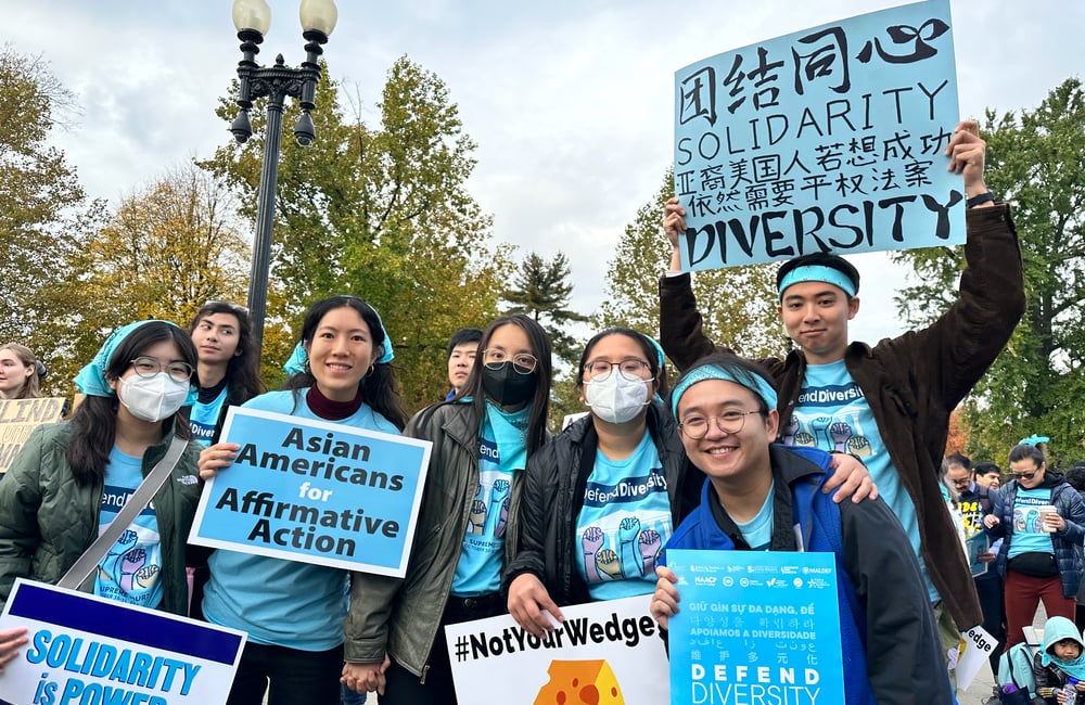 Students rally outside the Supreme Court in 2022, calling for race-conscious admissions and holding signs that say "Solidarity is Power" and "Not Your Wedge."