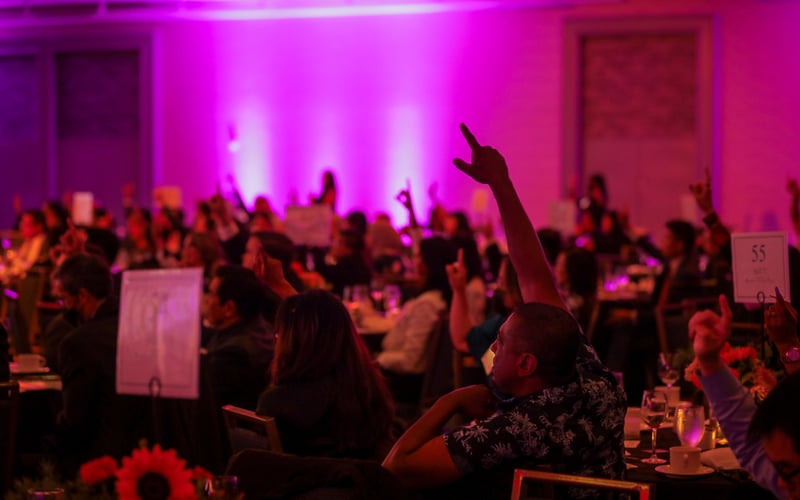 ALC supporters and community partners raise their hands at our 51st anniversary celebration.