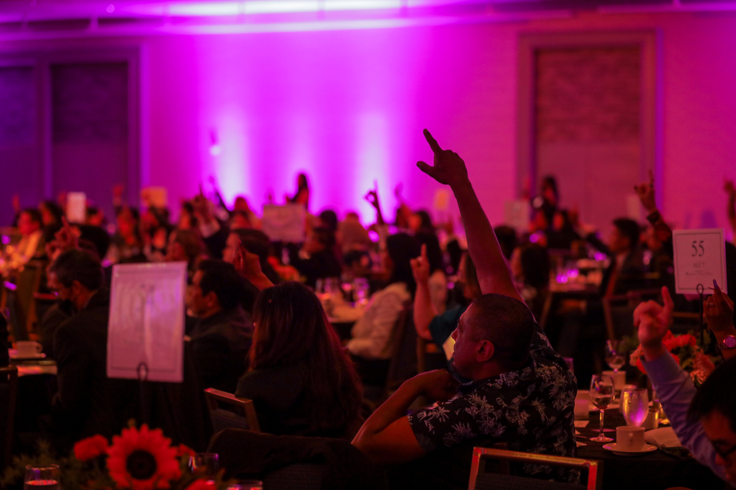 ALC supporters and community partners raise their hands at our 51st anniversary celebration.