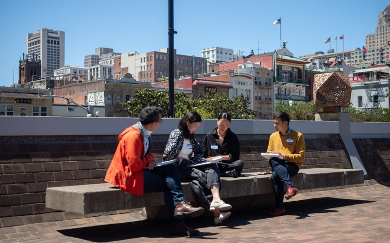 Four ALC staff members sit on a bench in San Francisco Chinatown.