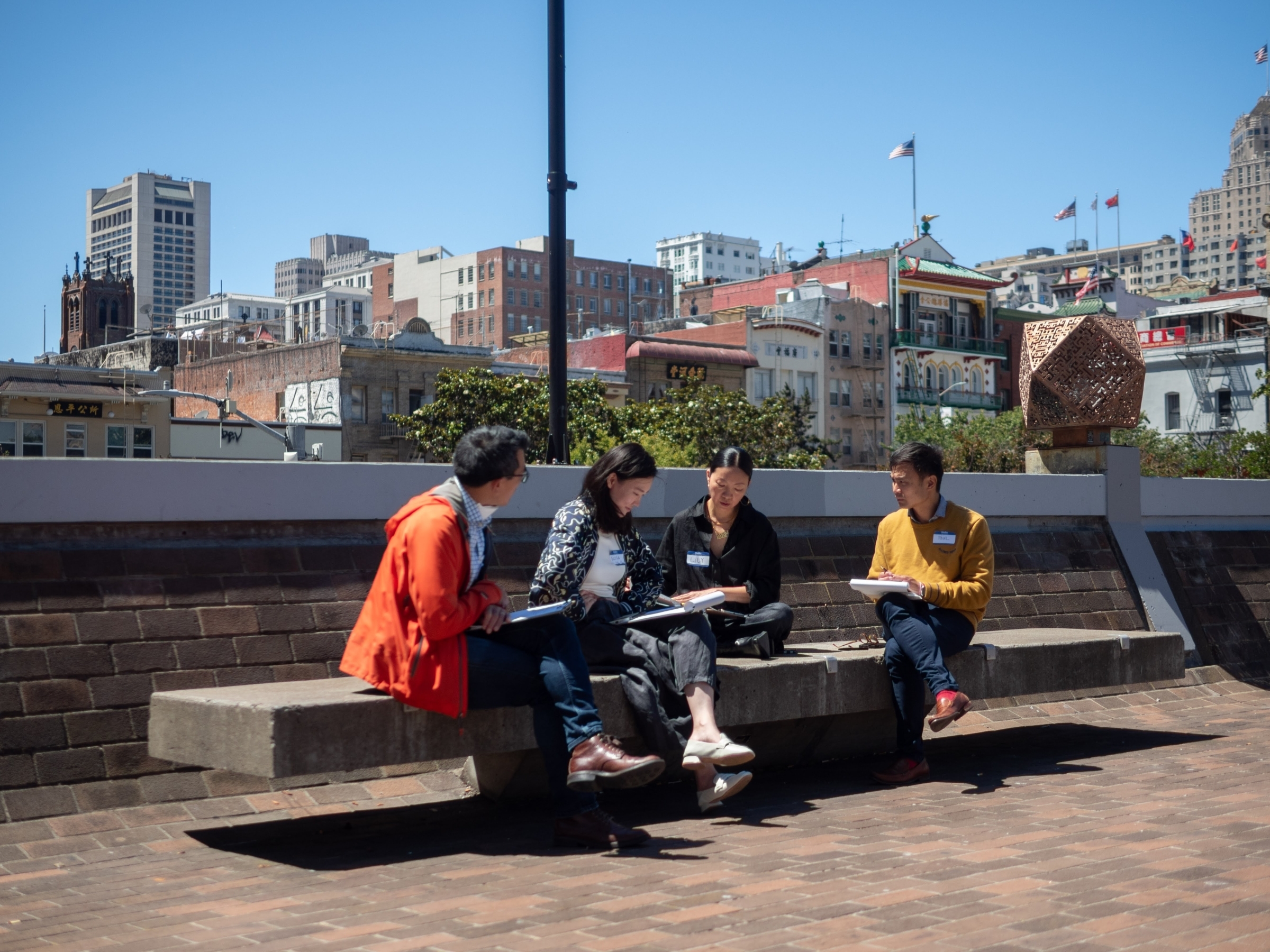Four ALC staff members sit on a bench in San Francisco Chinatown.