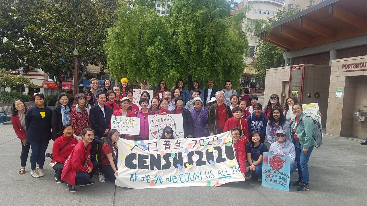 Dozens of San Francisco residents and advocates gather together behind a sign that says "Census 2020"