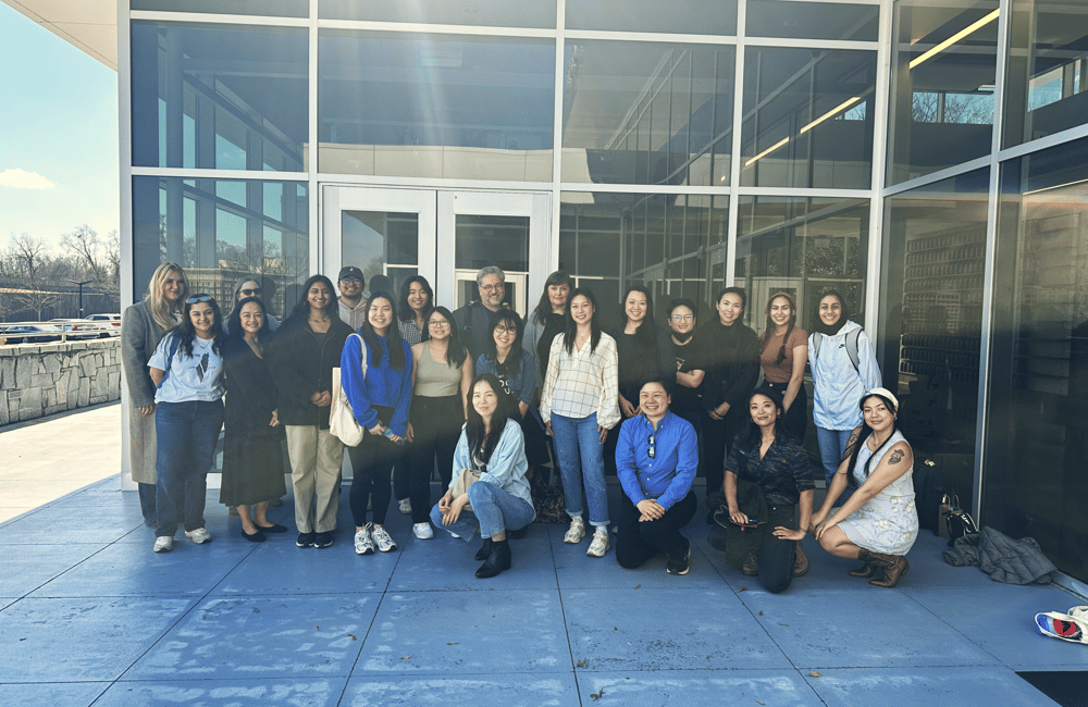 A large group photo is taken of 21 ALC staff members and one member of the Equal Justice Initiative staff member outside a museum.