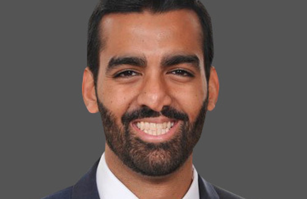 Hammad Alam wearing a dark gray suit and blue tie.