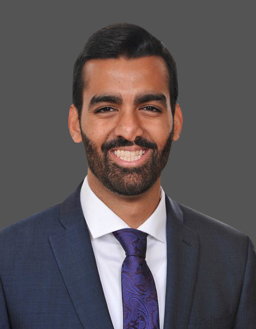 Hammad Alam wearing a dark gray suit and blue tie.