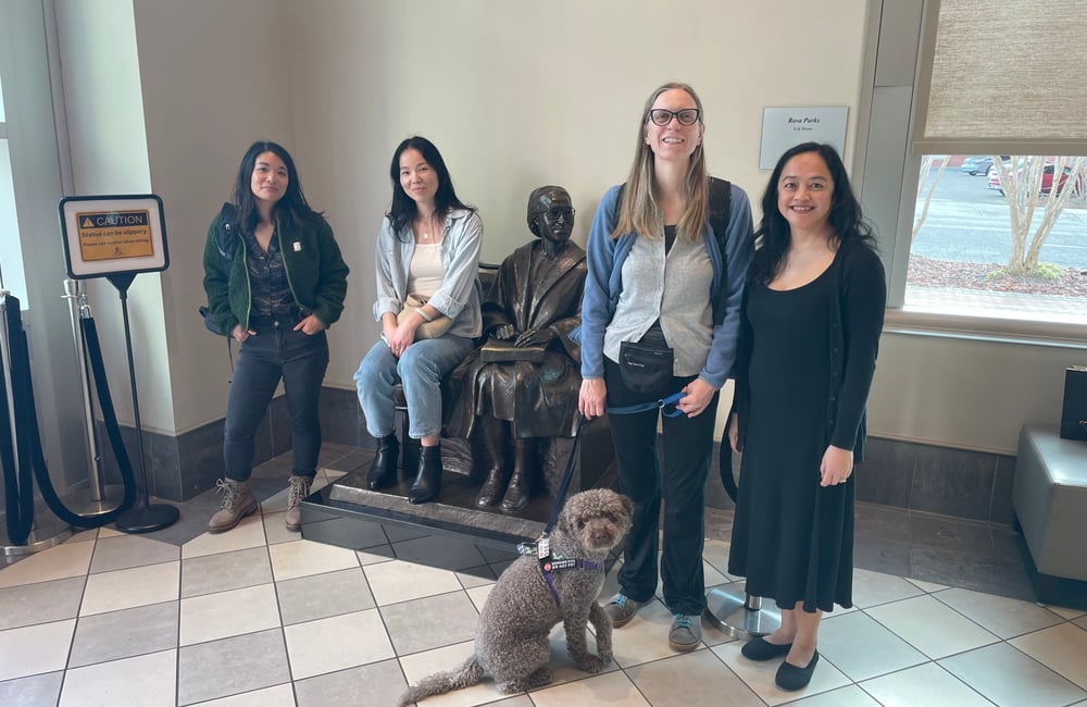 Four staff members stand by a statue of a seated Rosa Parks in the Rosa Parks Museum.