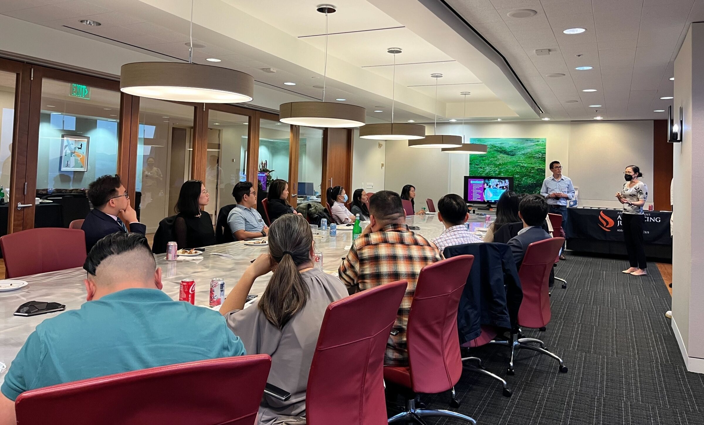 Eileen Kim speaks at the front of the room to a group of members sitting at a conference table.