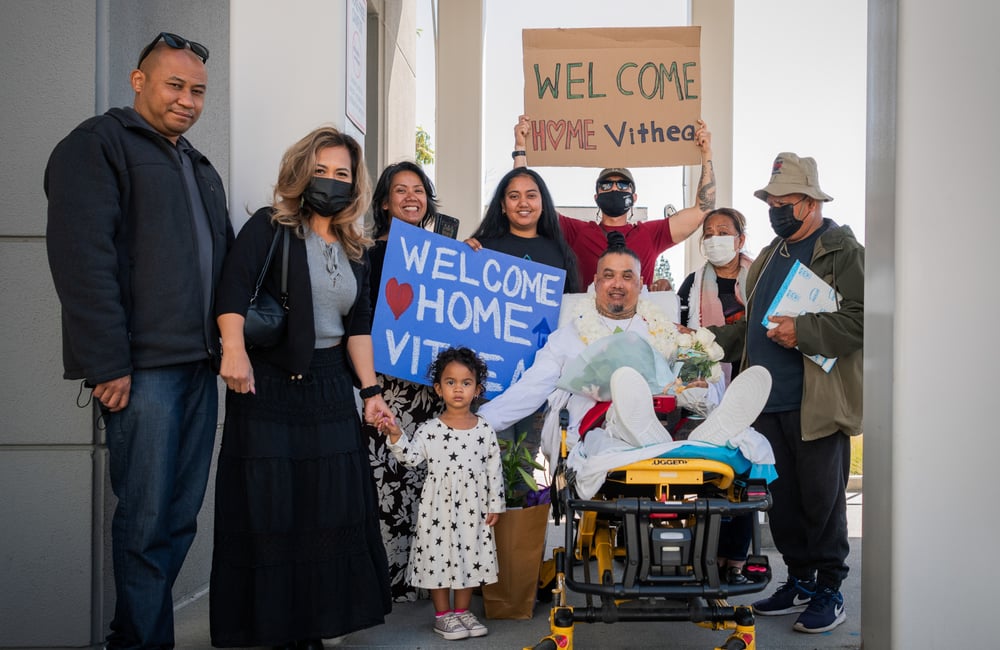 Vithea is surrounded by smiling family and community welcoming him home.